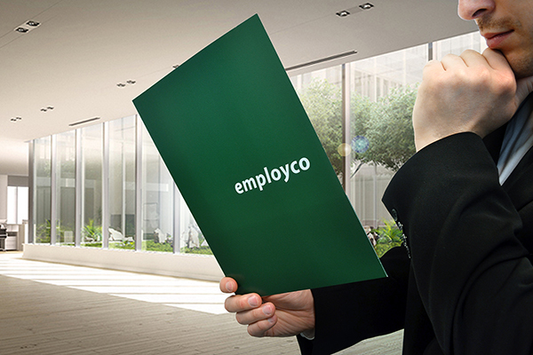 Man in suit holding in one hand Employco booklet and his chin in thought with the other hand.