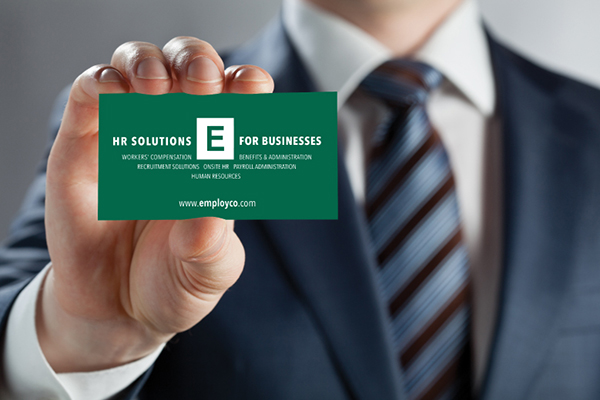 Man in suit holding Employco USA business card.