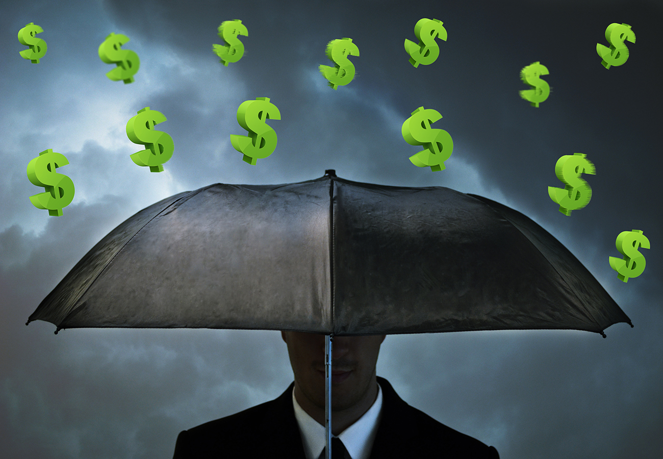 Man holding umbrella protecting from raining dollar signs.